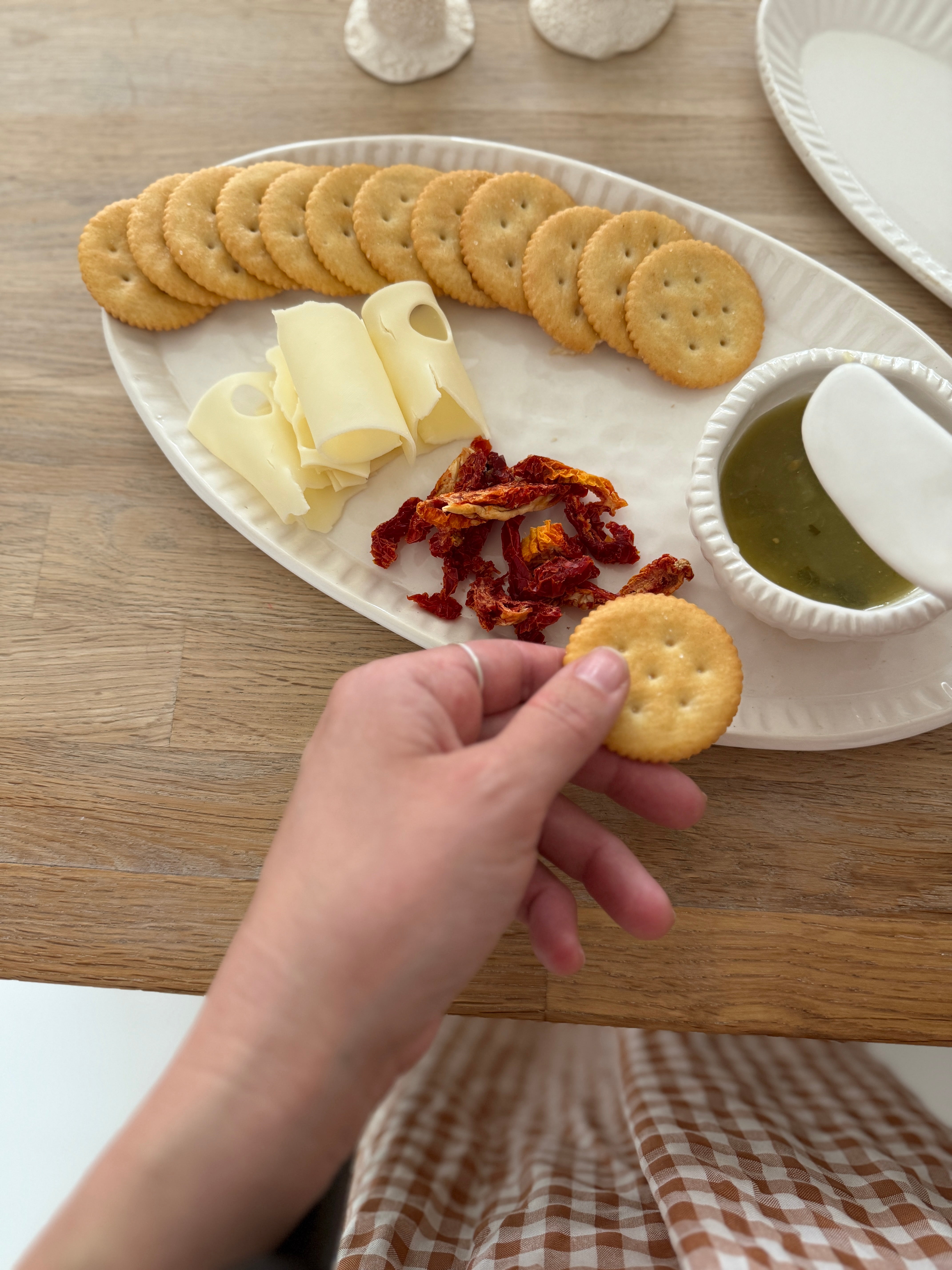 Handmade ceramic servingware with hand-carved line texture — oval platter, dip bowls, and a spread knife.
