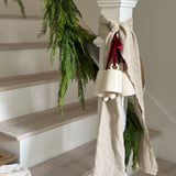 Handmade ceramic holiday bell ornament with a white eggshell finish and red velvet ribbon