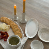 Handmade ceramic servingware with hand-carved line texture — oval platter, dip bowls, and a spread knife.