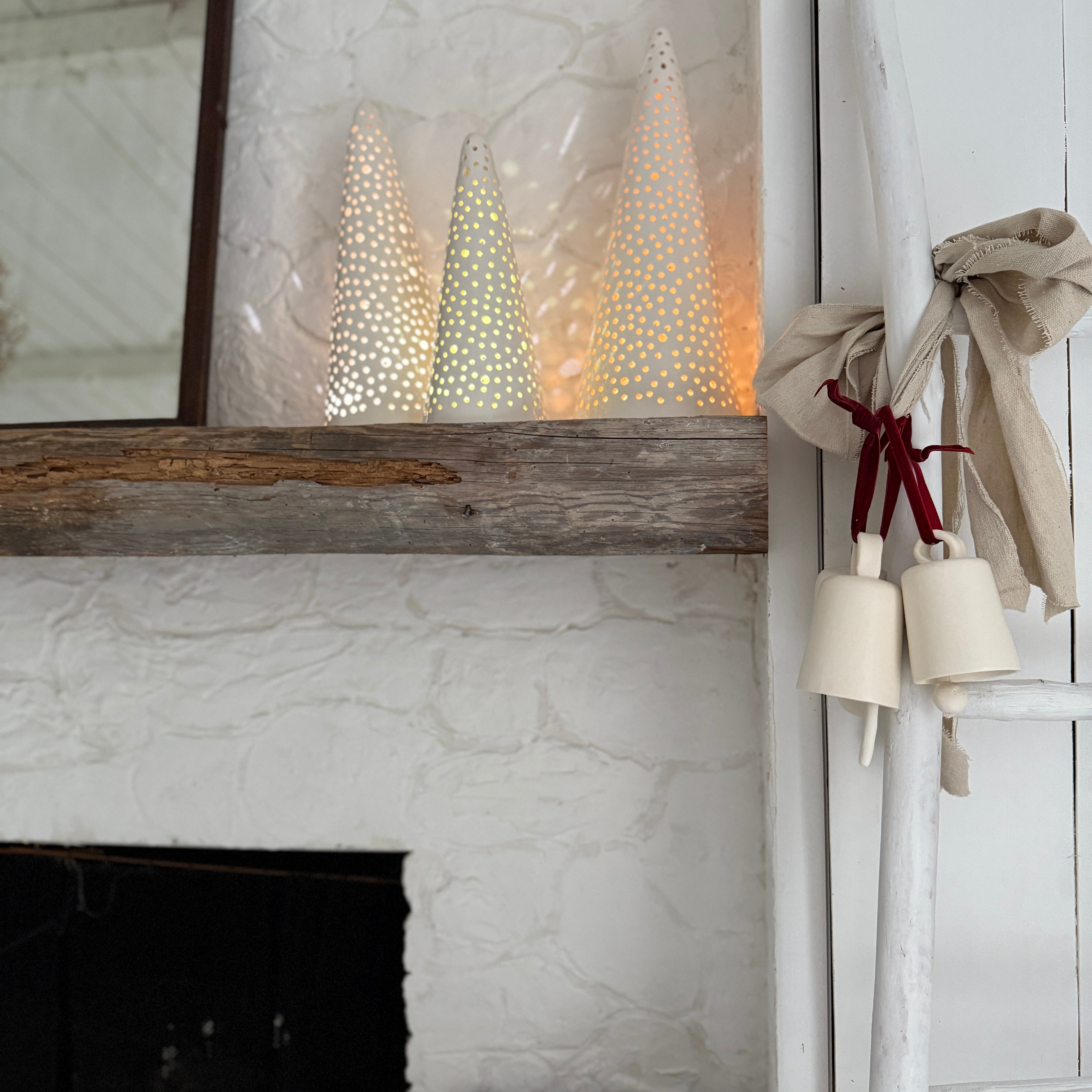 Handmade stoneware tree luminary with star cutouts glowing from an LED tea light