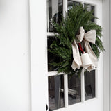 Handmade ceramic holiday bell ornament with a white eggshell finish and red velvet ribbon