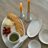 Handmade ceramic servingware with hand-carved line texture — oval platter, dip bowls, and a spread knife.