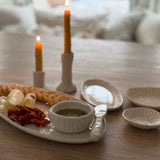 Handmade ceramic servingware with hand-carved line texture — oval platter, dip bowls, and a spread knife.