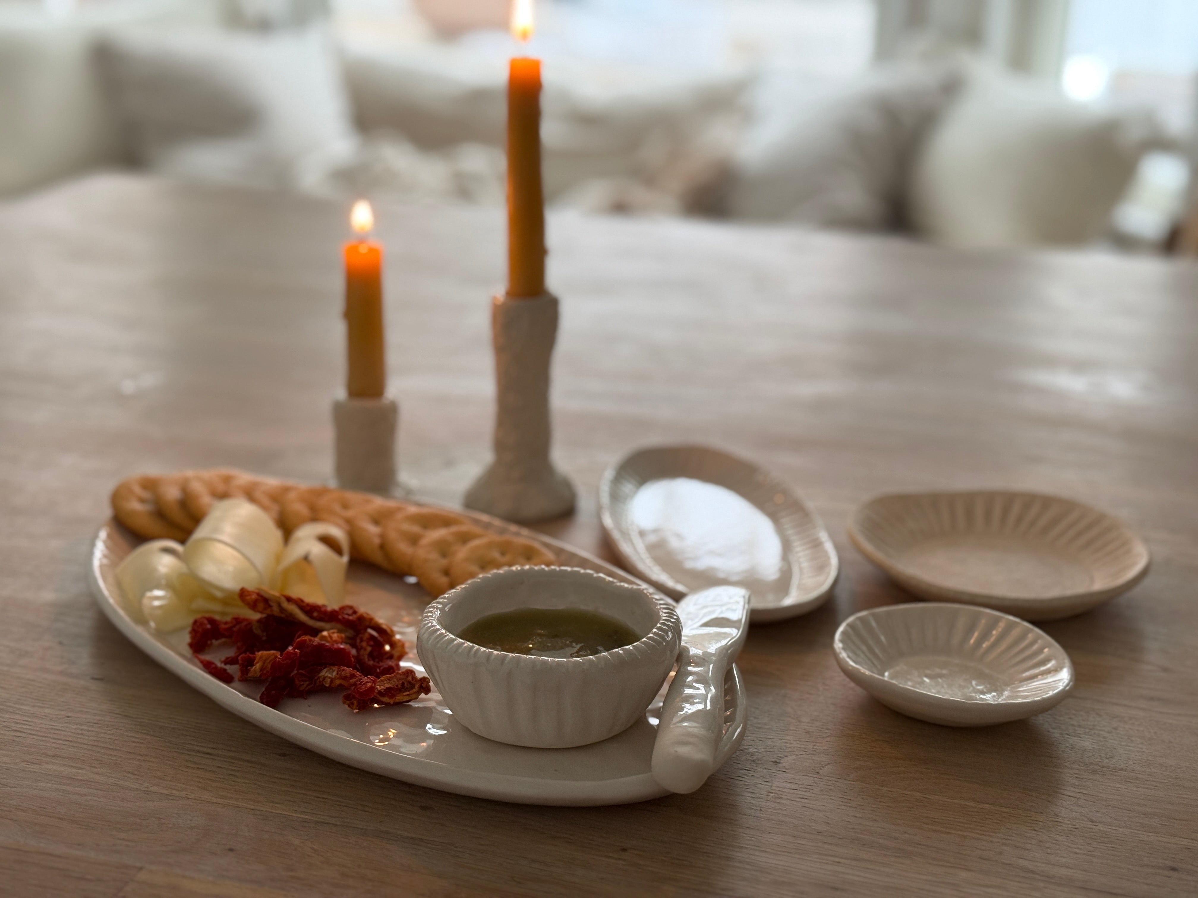 Handmade ceramic servingware with hand-carved line texture — oval platter, dip bowls, and a spread knife.