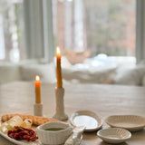 Handmade ceramic servingware with hand-carved line texture — oval platter, dip bowls, and a spread knife.