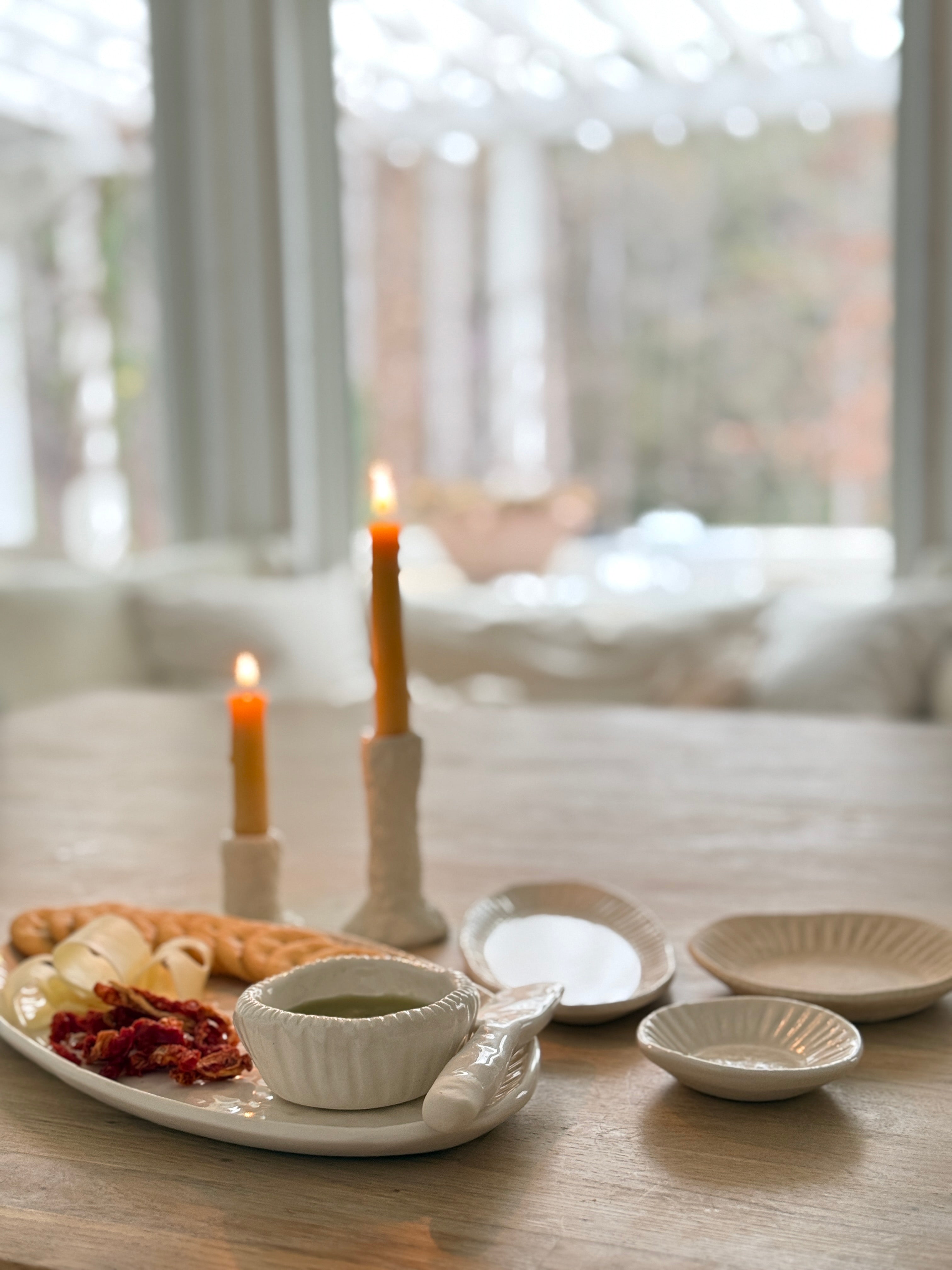 Handmade ceramic servingware with hand-carved line texture — oval platter, dip bowls, and a spread knife.