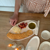 Handmade ceramic servingware with hand-carved line texture — oval platter, dip bowls, and a spread knife.