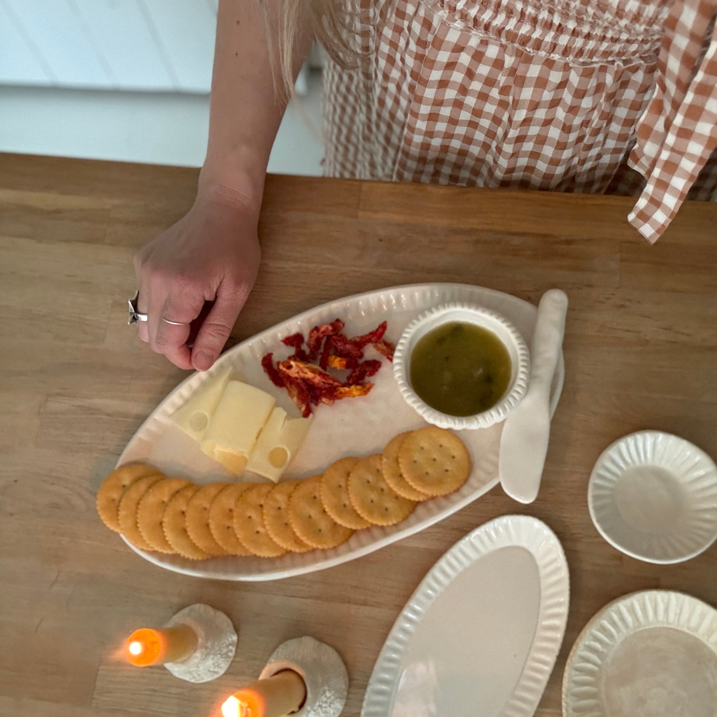 Handmade ceramic servingware with hand-carved line texture — oval platter, dip bowls, and a spread knife.