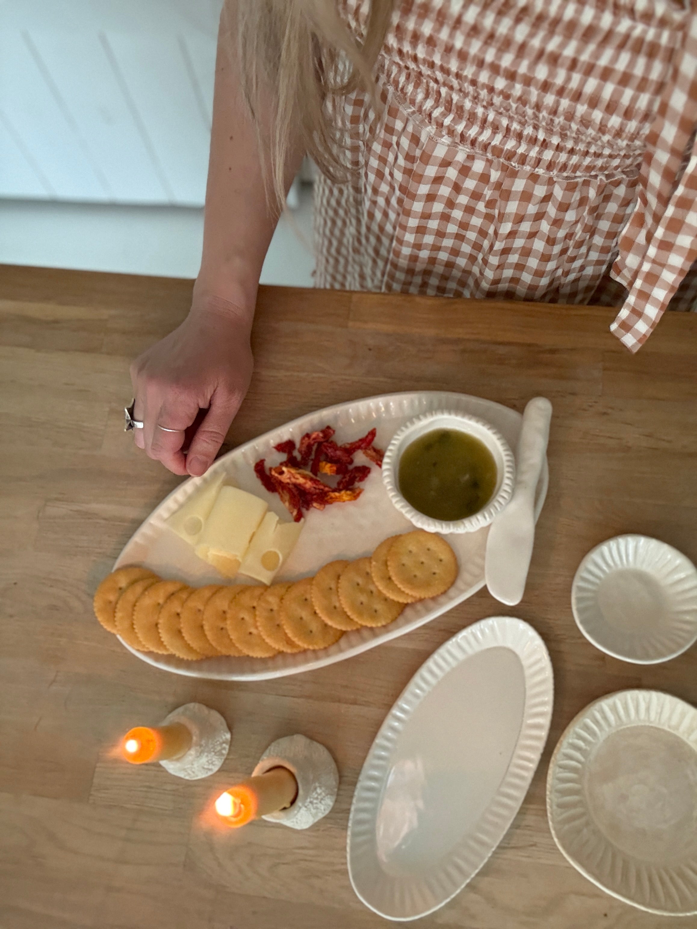 Handmade ceramic servingware with hand-carved line texture — oval platter, dip bowls, and a spread knife.