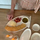 Handmade ceramic servingware with hand-carved line texture — oval platter, dip bowls, and a spread knife.