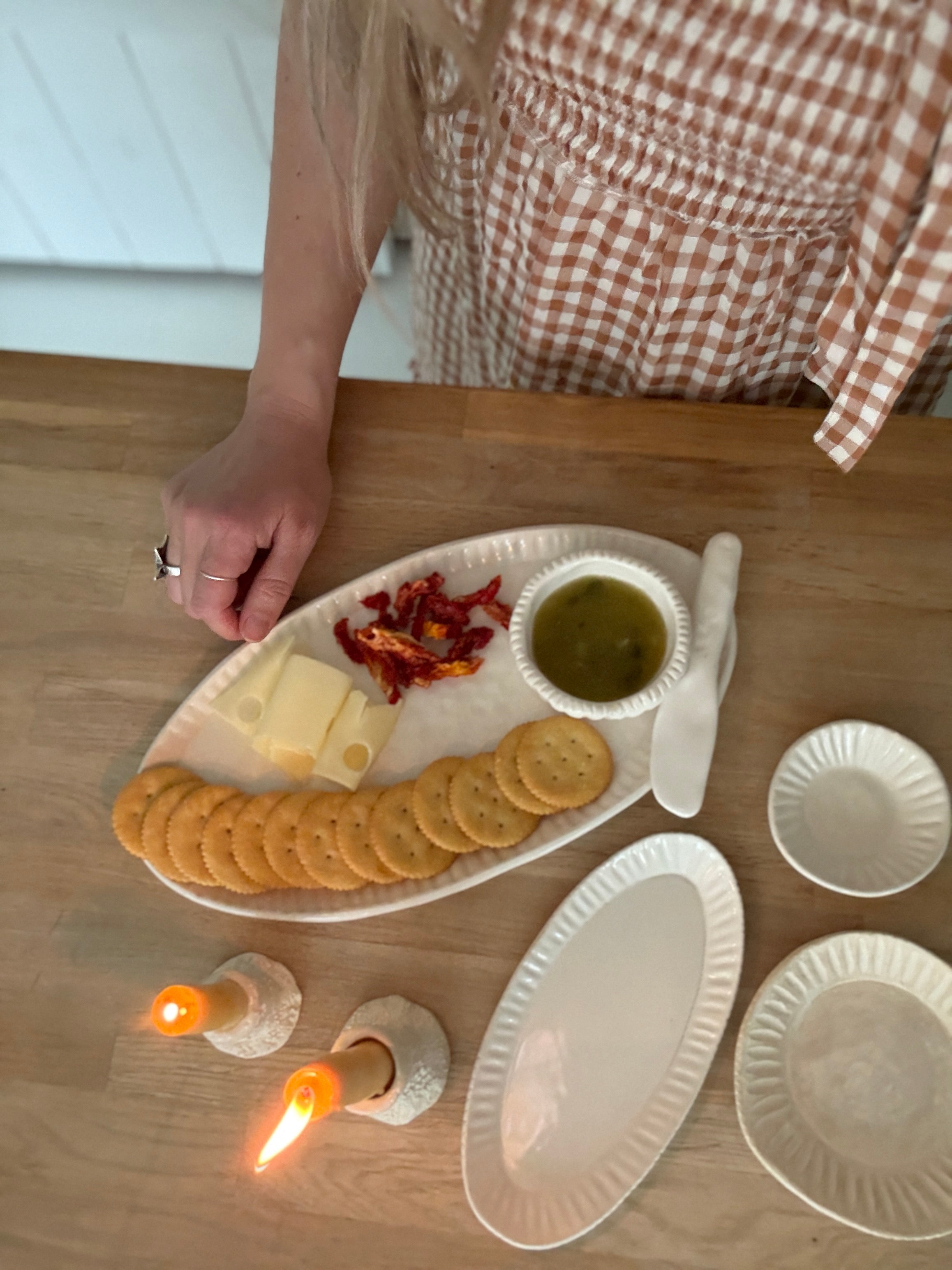 Handmade ceramic servingware with hand-carved line texture — oval platter, dip bowls, and a spread knife.