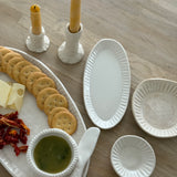Handmade ceramic servingware with hand-carved line texture — oval platter, dip bowls, and a spread knife.