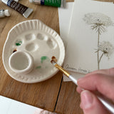 Handmade ceramic watercolor paint palette with mixing wells, a small water cup, and a brush holder.