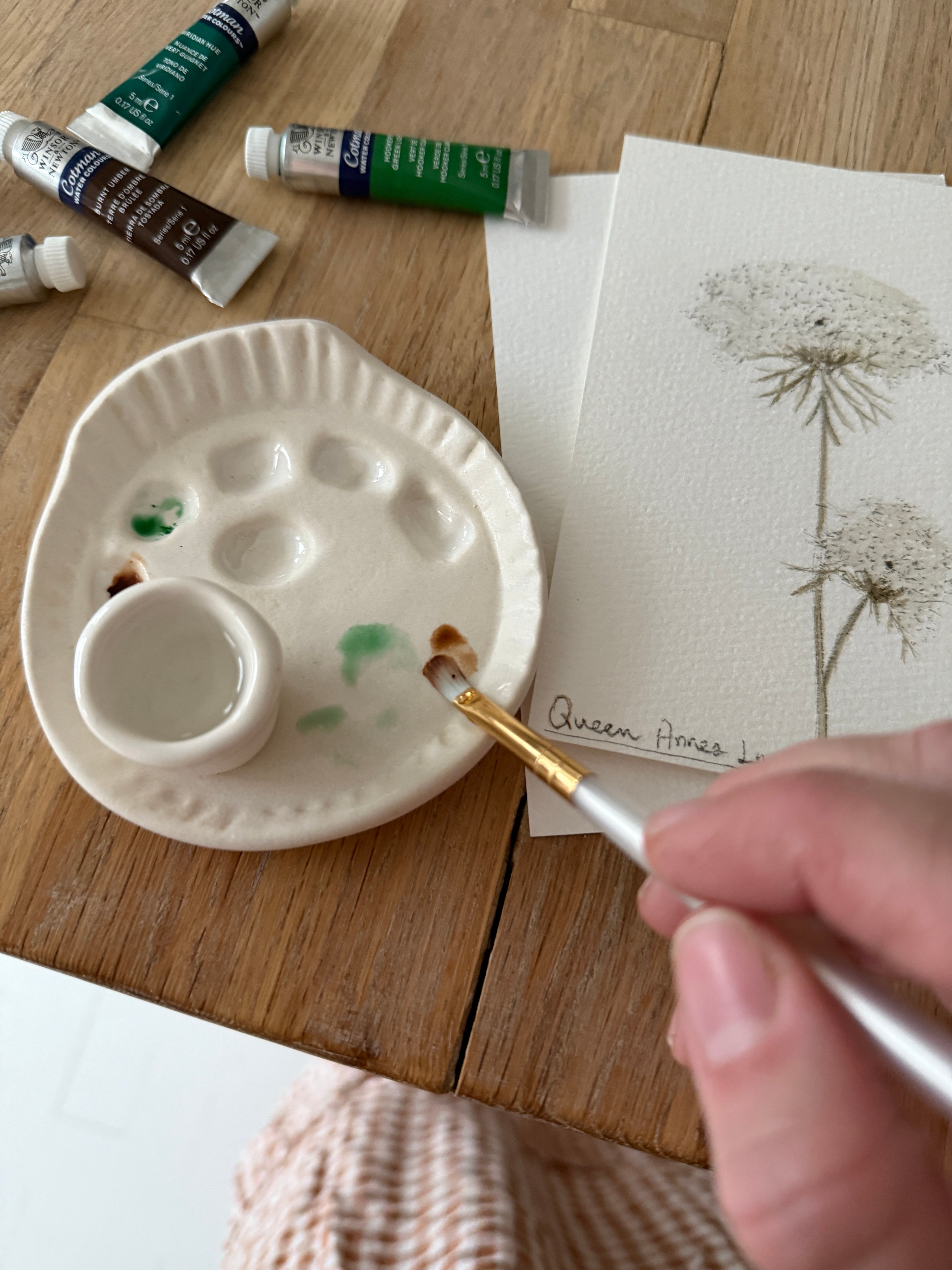 Handmade ceramic watercolor paint palette with mixing wells, a small water cup, and a brush holder.