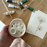 Handmade ceramic watercolor paint palette with mixing wells, a small water cup, and a brush holder.