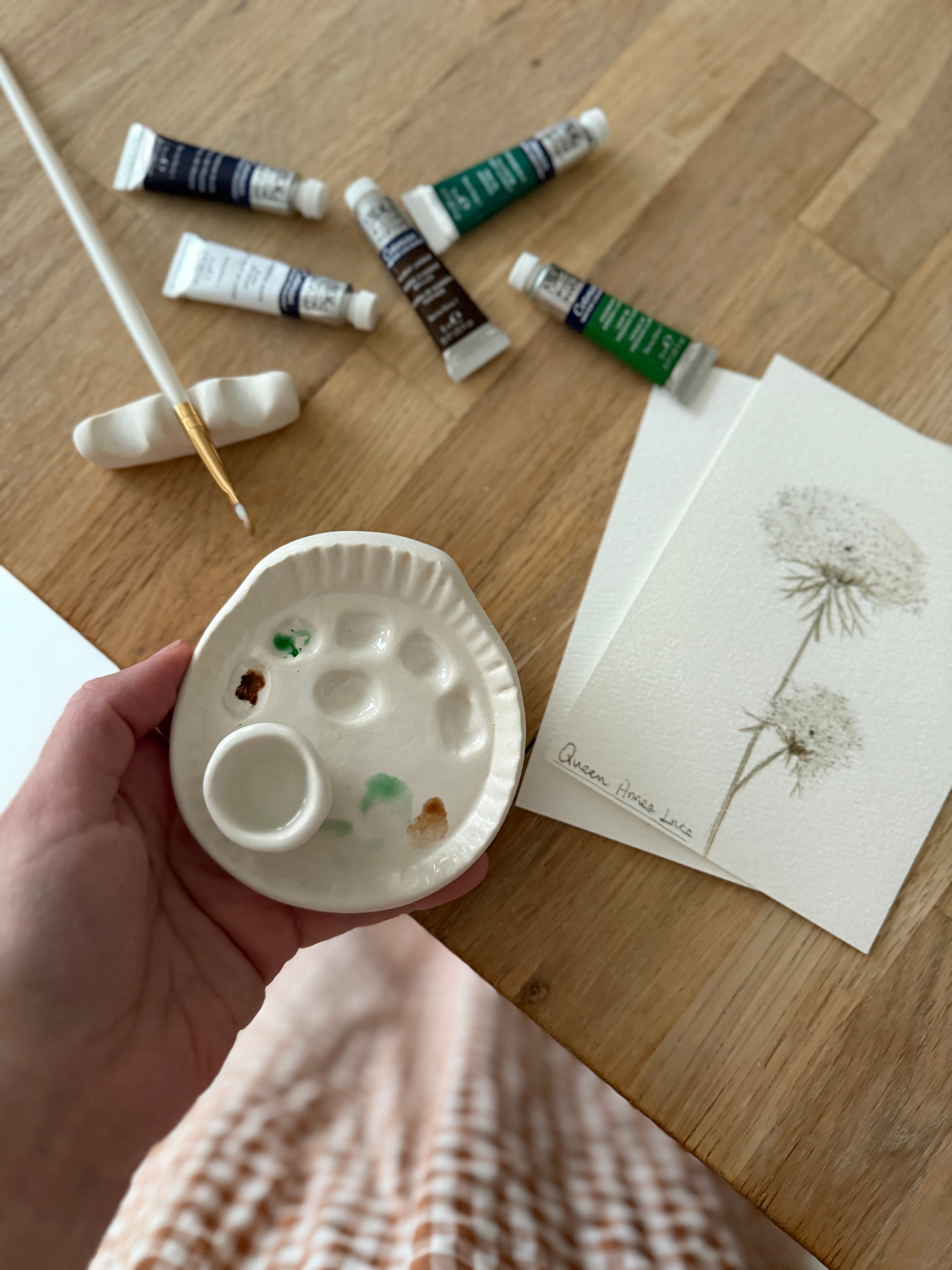 Handmade ceramic watercolor paint palette with mixing wells, a small water cup, and a brush holder.