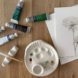 Handmade ceramic watercolor paint palette with mixing wells, a small water cup, and a brush holder.