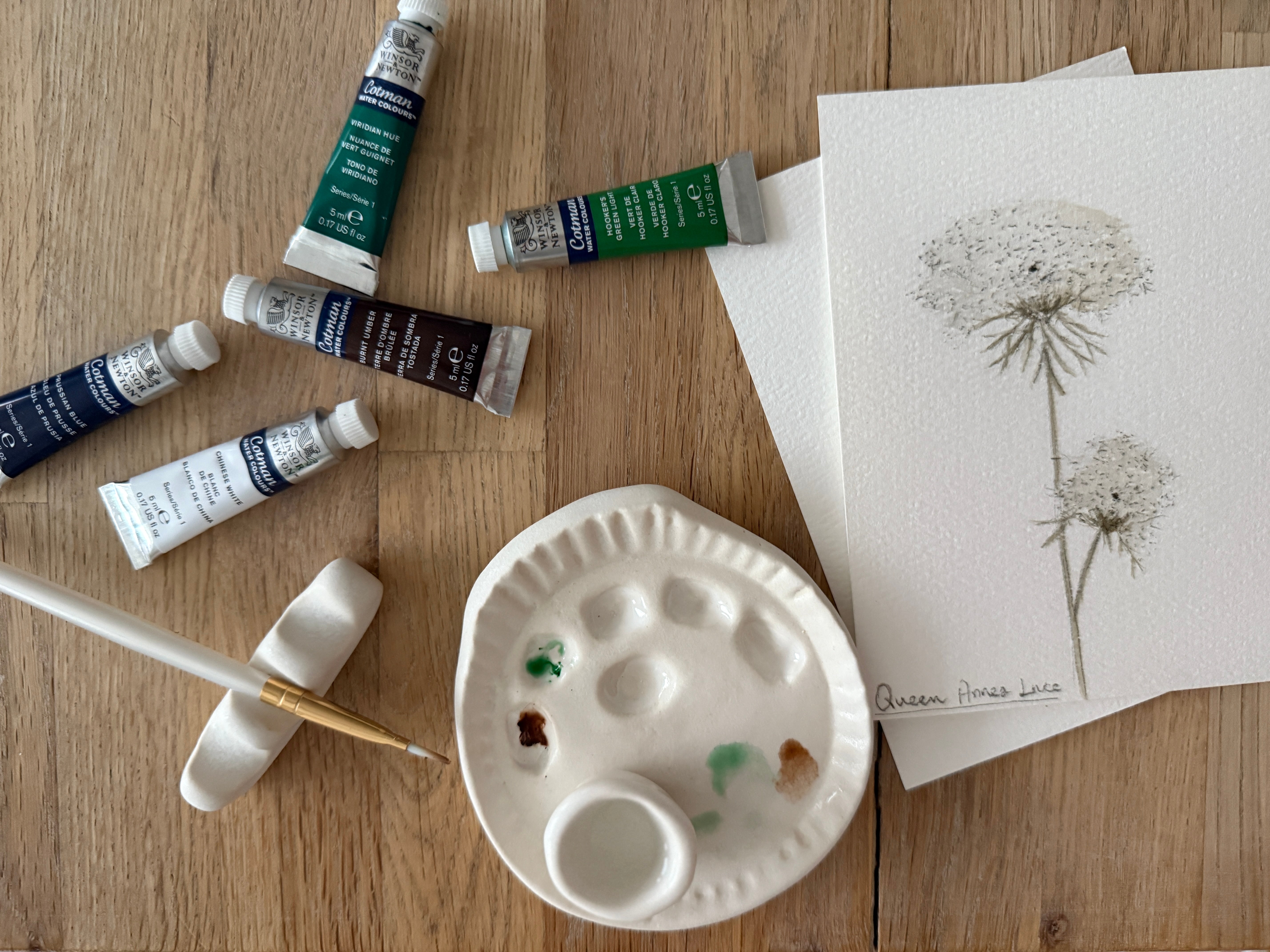 Handmade ceramic watercolor paint palette with mixing wells, a small water cup, and a brush holder.