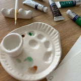 Handmade ceramic watercolor paint palette with mixing wells, a small water cup, and a brush holder.