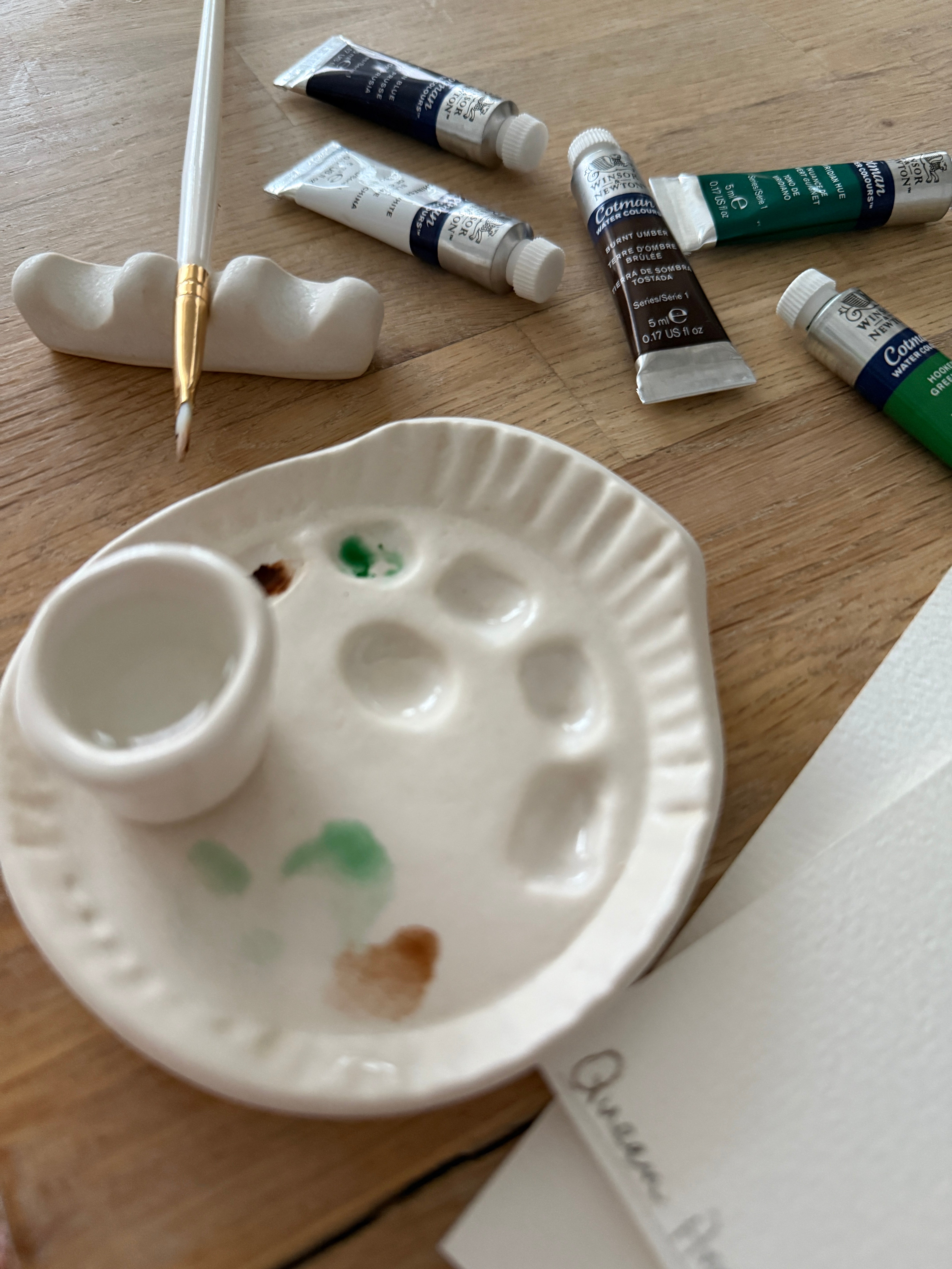 Handmade ceramic watercolor paint palette with mixing wells, a small water cup, and a brush holder.