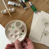 Handmade ceramic watercolor paint palette with mixing wells, a small water cup, and a brush holder.