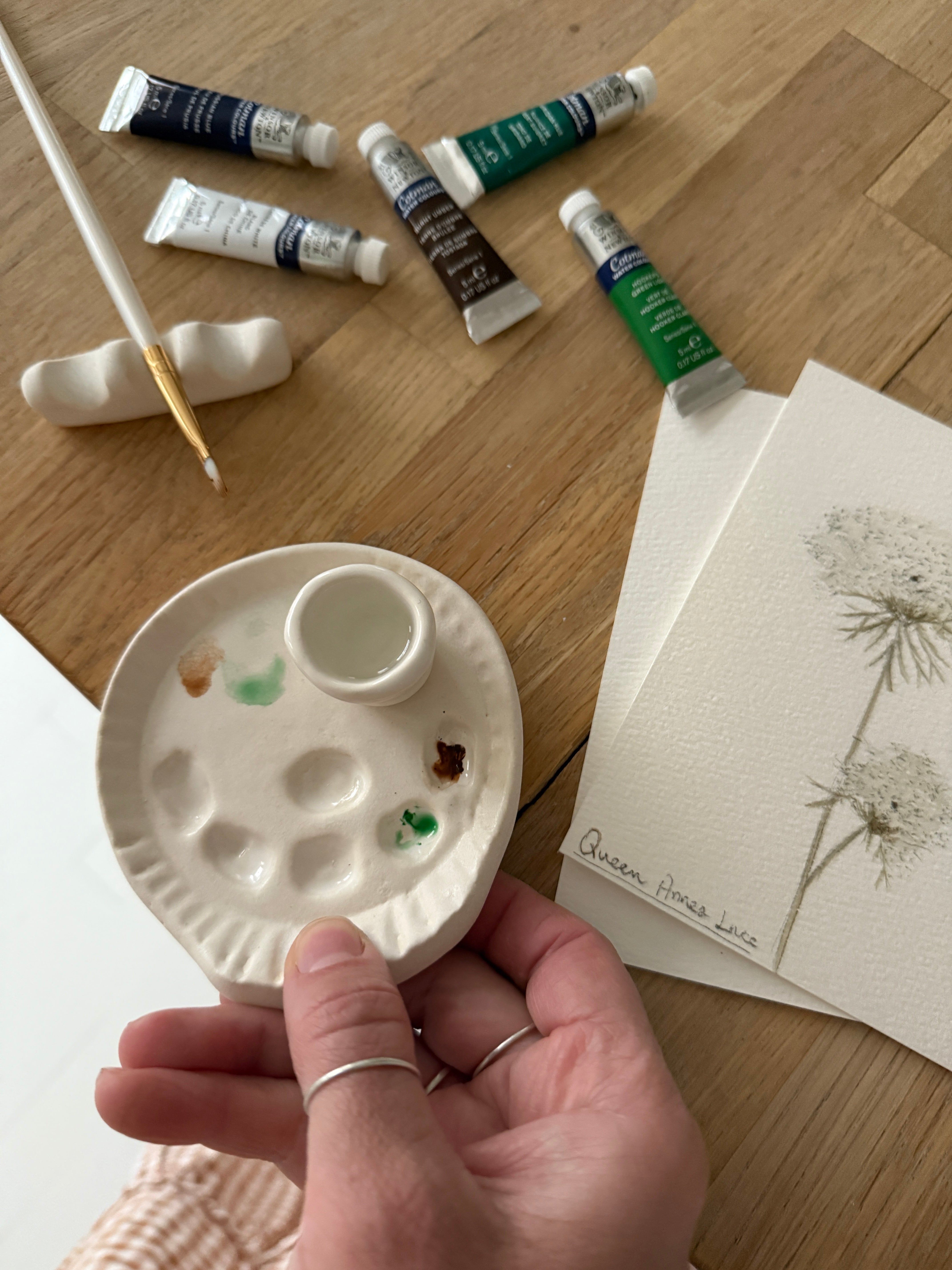 Handmade ceramic watercolor paint palette with mixing wells, a small water cup, and a brush holder.