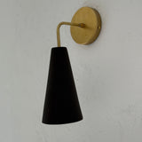 Handmade conical ceramic wall sconce in espresso finish, casting a warm downward glow