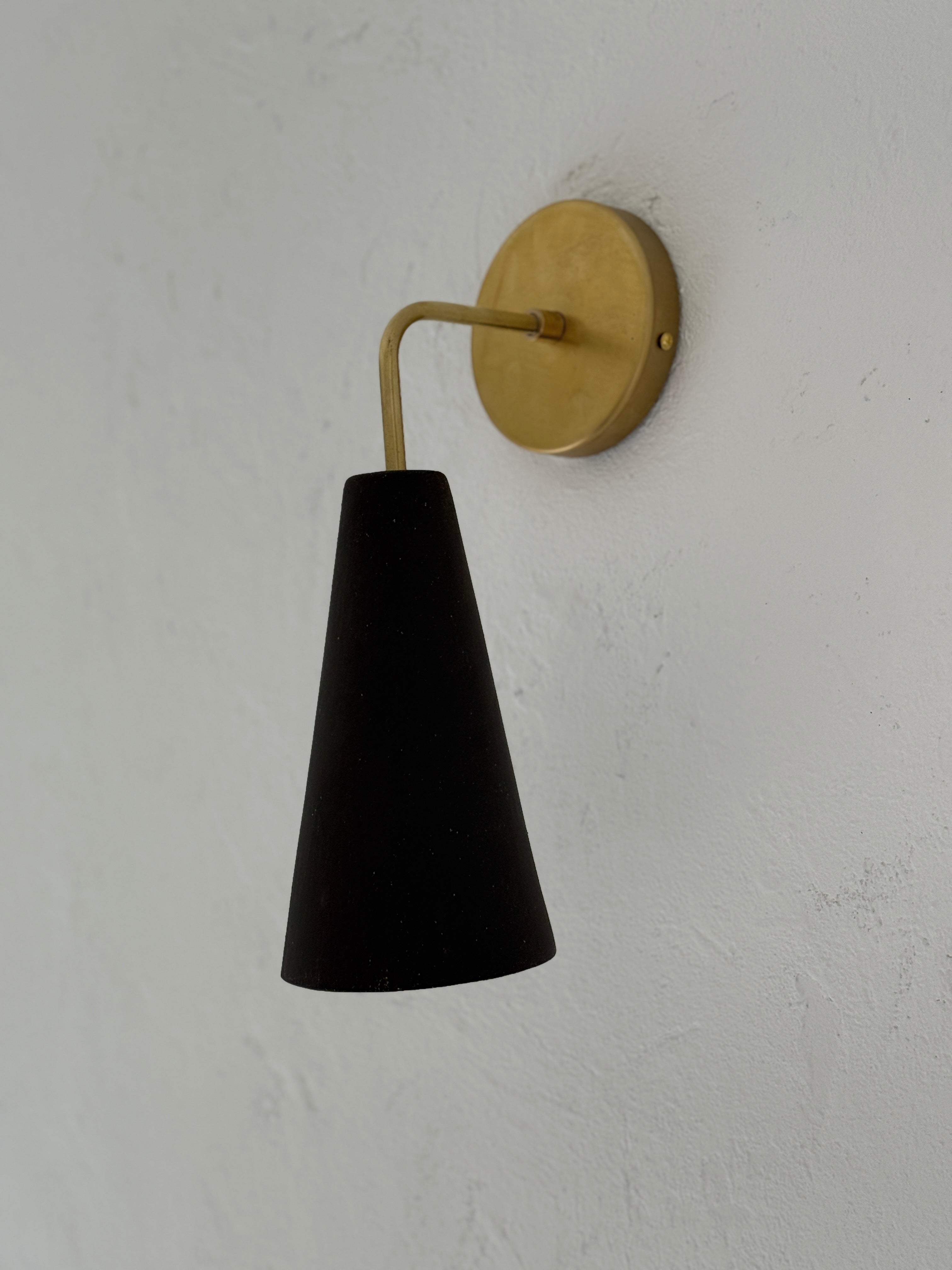 Handmade conical ceramic wall sconce in espresso finish, casting a warm downward glow