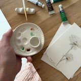 Handmade ceramic watercolor paint palette with mixing wells, a small water cup, and a brush holder.