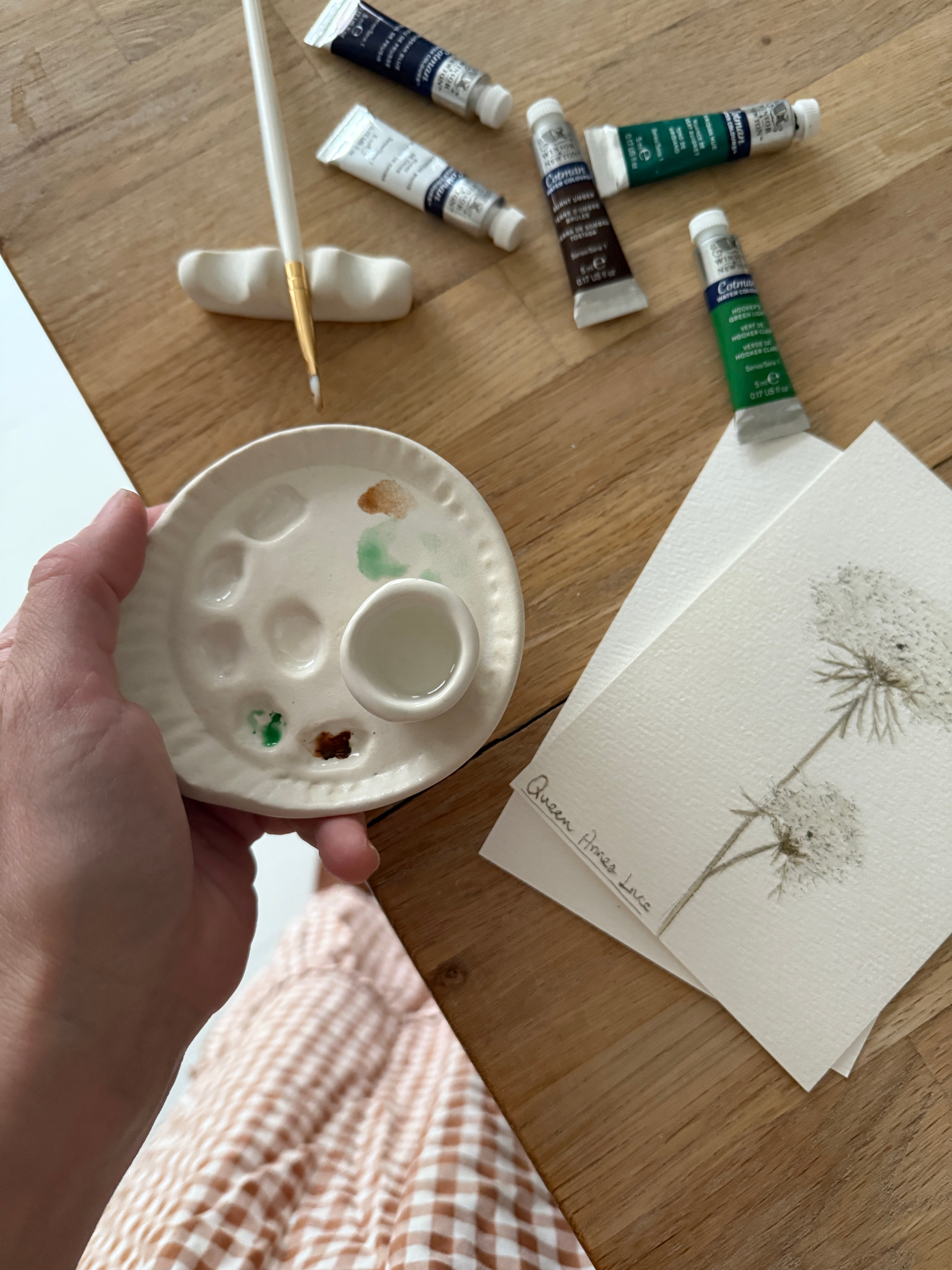 Handmade ceramic watercolor paint palette with mixing wells, a small water cup, and a brush holder.