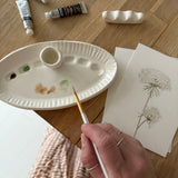 Handmade ceramic watercolor paint palette with mixing wells, a small water cup, and a brush holder.