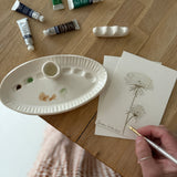Handmade ceramic watercolor paint palette with mixing wells, a small water cup, and a brush holder.