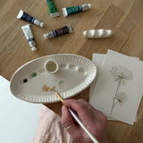 Handmade ceramic watercolor paint palette with mixing wells, a small water cup, and a brush holder.