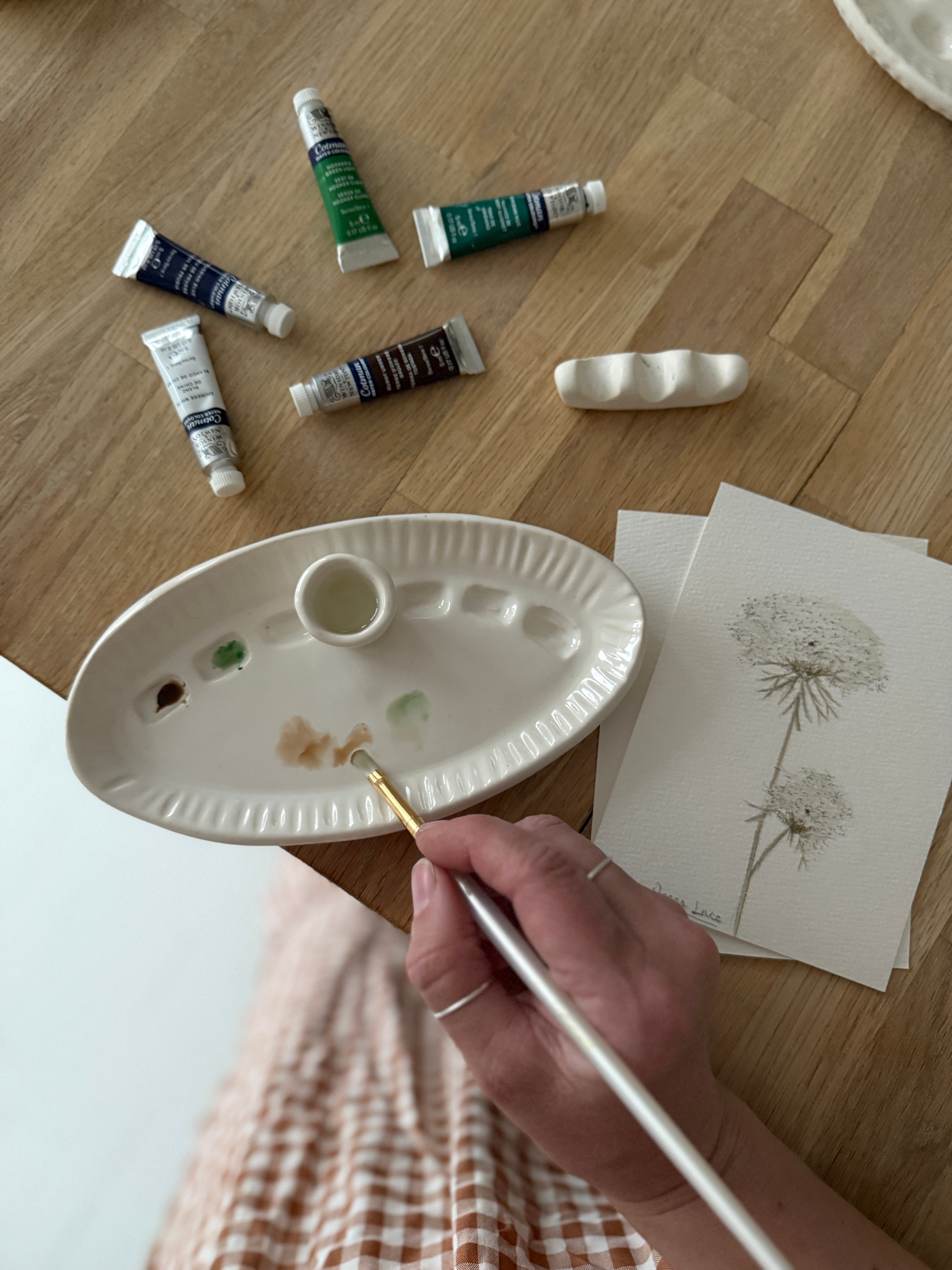 Handmade ceramic watercolor paint palette with mixing wells, a small water cup, and a brush holder.