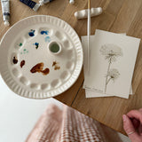 Handmade ceramic watercolor paint palette with mixing wells, a small water cup, and a brush holder.