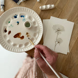 Handmade ceramic watercolor paint palette with mixing wells, a small water cup, and a brush holder.