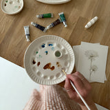 Handmade ceramic watercolor paint palette with mixing wells, a small water cup, and a brush holder.