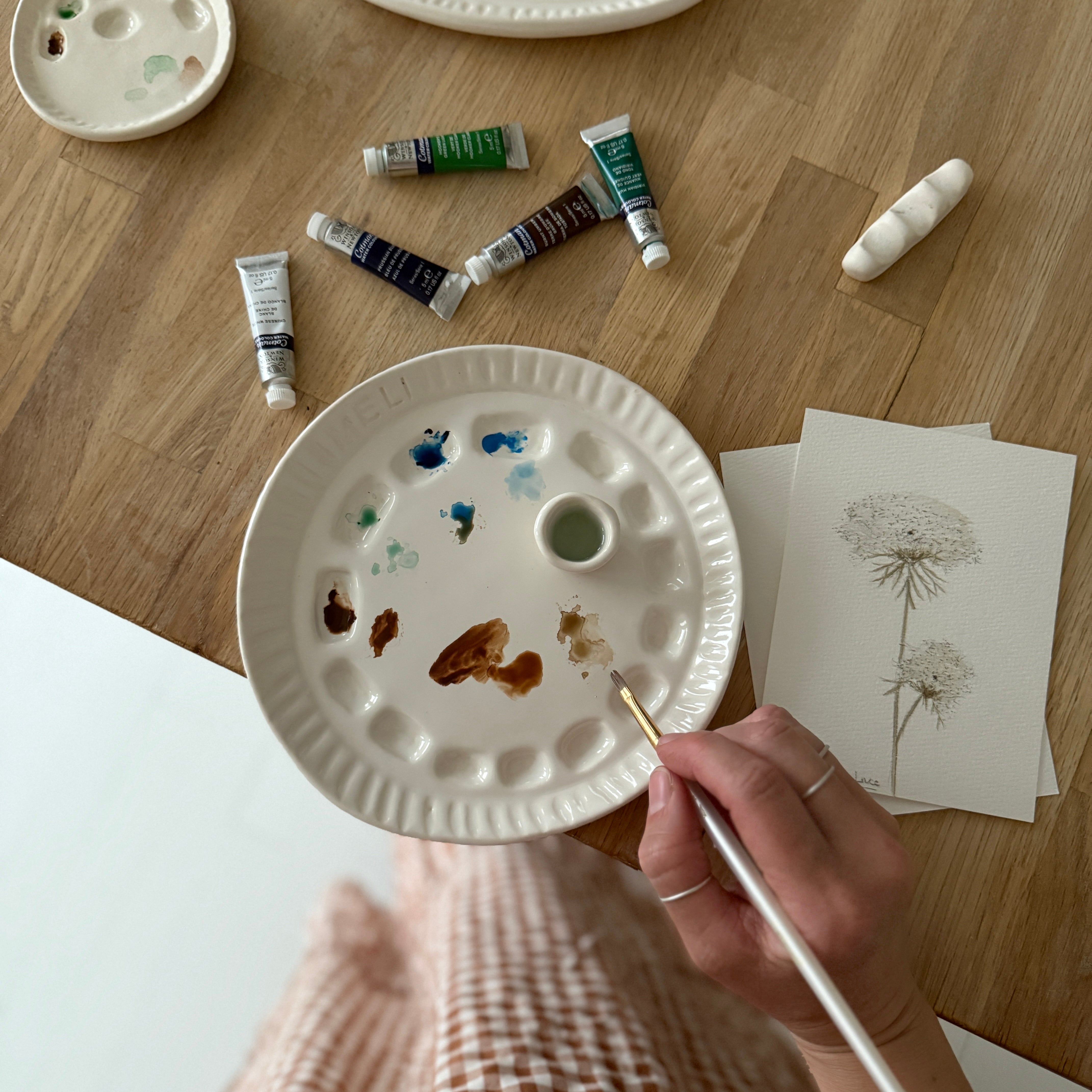 Handmade ceramic watercolor paint palette with mixing wells, a small water cup, and a brush holder.