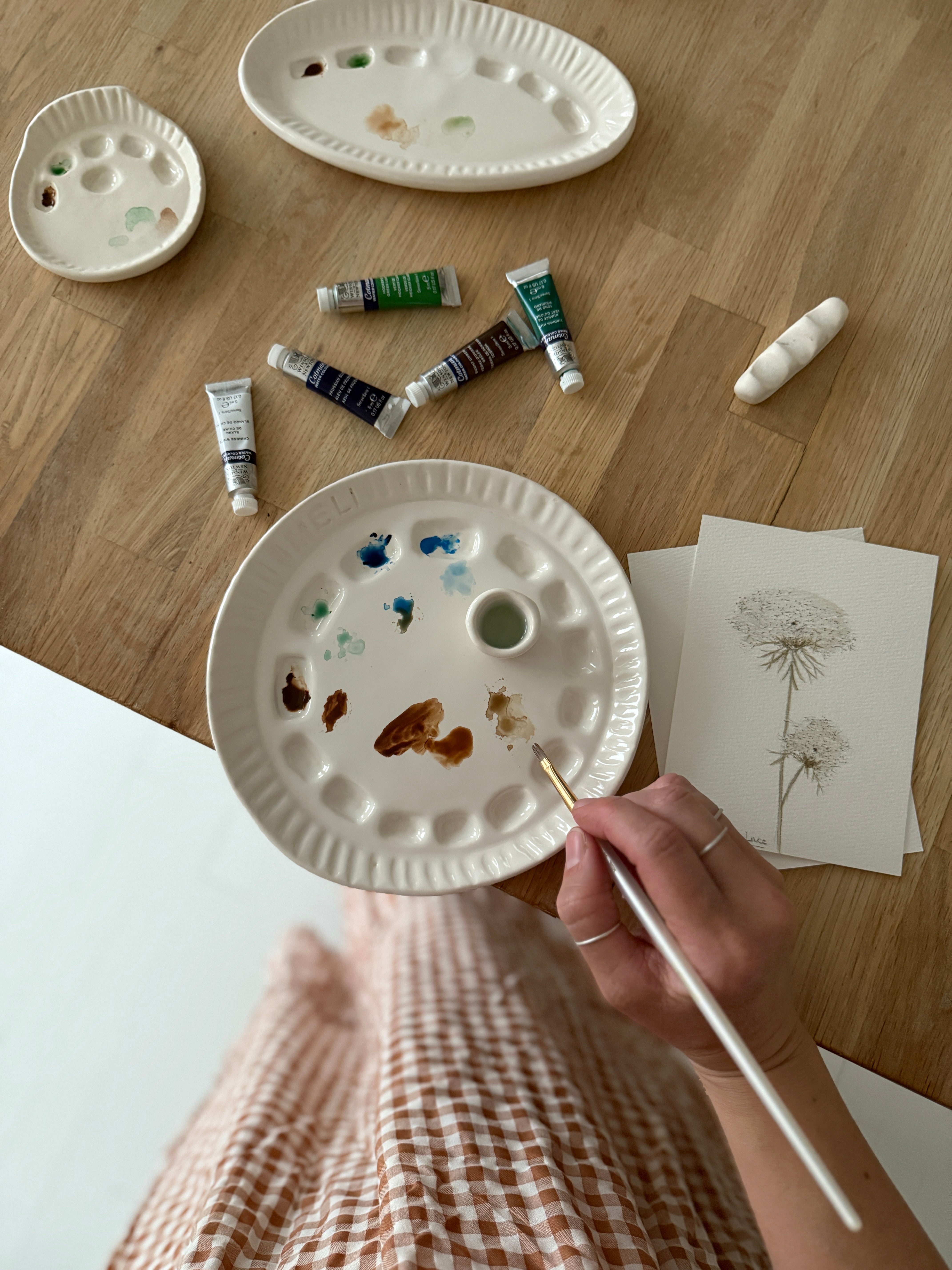 Handmade ceramic watercolor paint palette with mixing wells, a small water cup, and a brush holder.