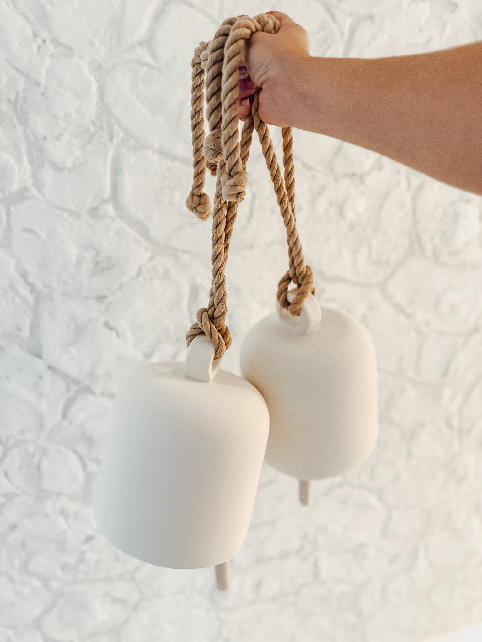 Handmade ceramic Loki bell in a neutral finish, hung for indoor or covered outdoor decor
