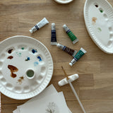 Handmade ceramic watercolor paint palette with mixing wells, a small water cup, and a brush holder.