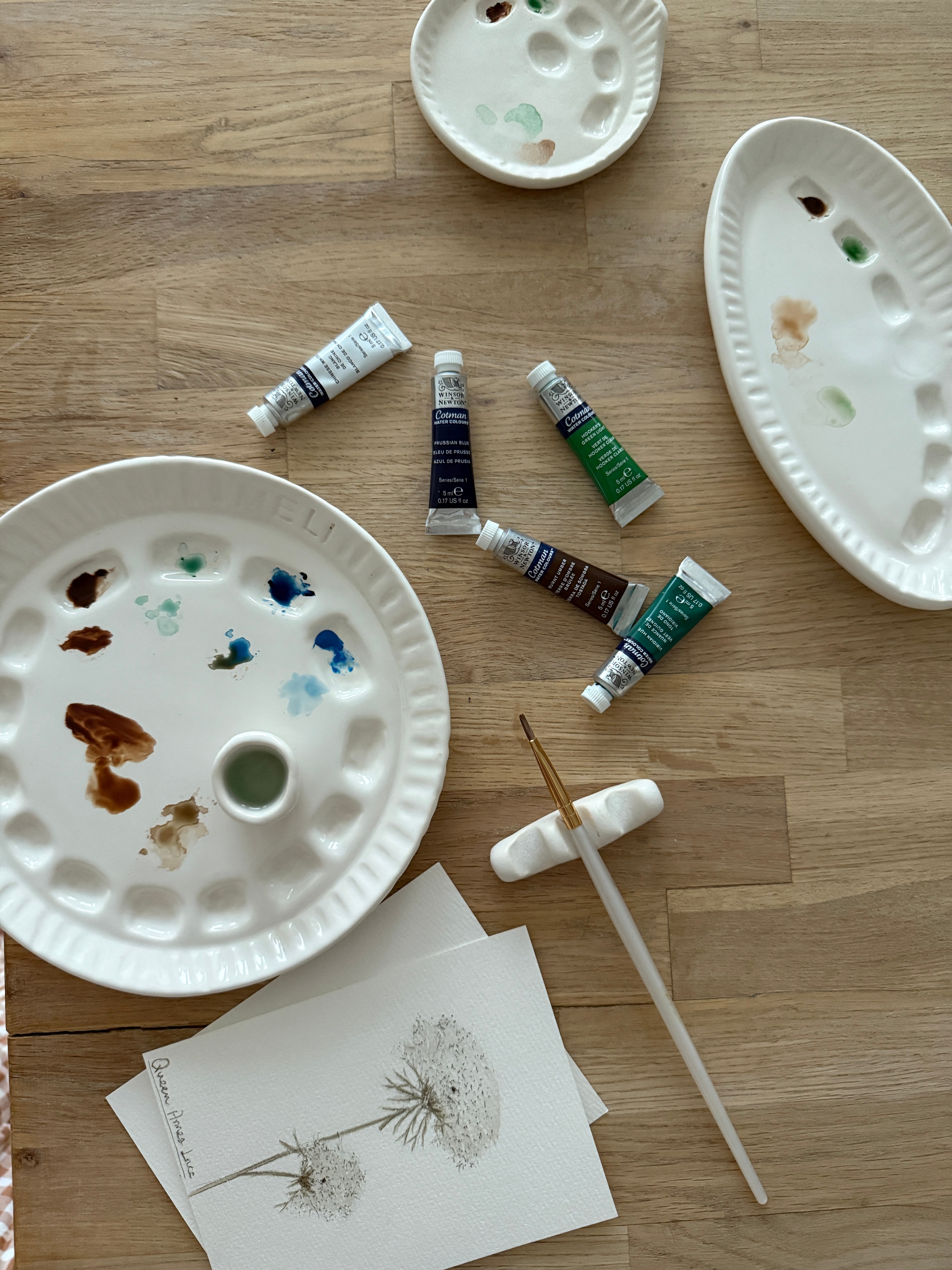 Handmade ceramic watercolor paint palette with mixing wells, a small water cup, and a brush holder.