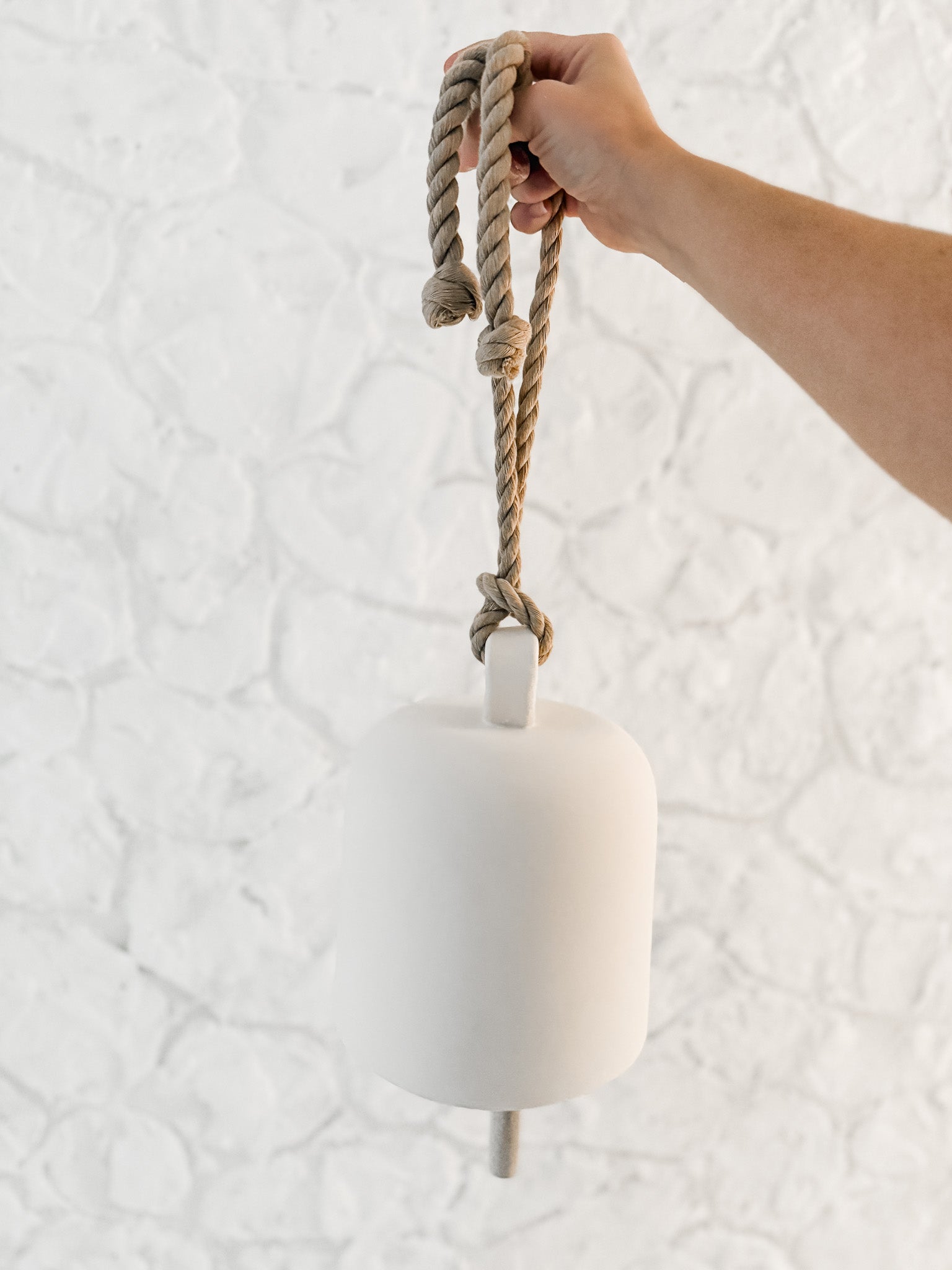 Handmade ceramic Loki bell in a neutral finish, hung for indoor or covered outdoor decor