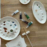 Handmade ceramic watercolor paint palette with mixing wells, a small water cup, and a brush holder.