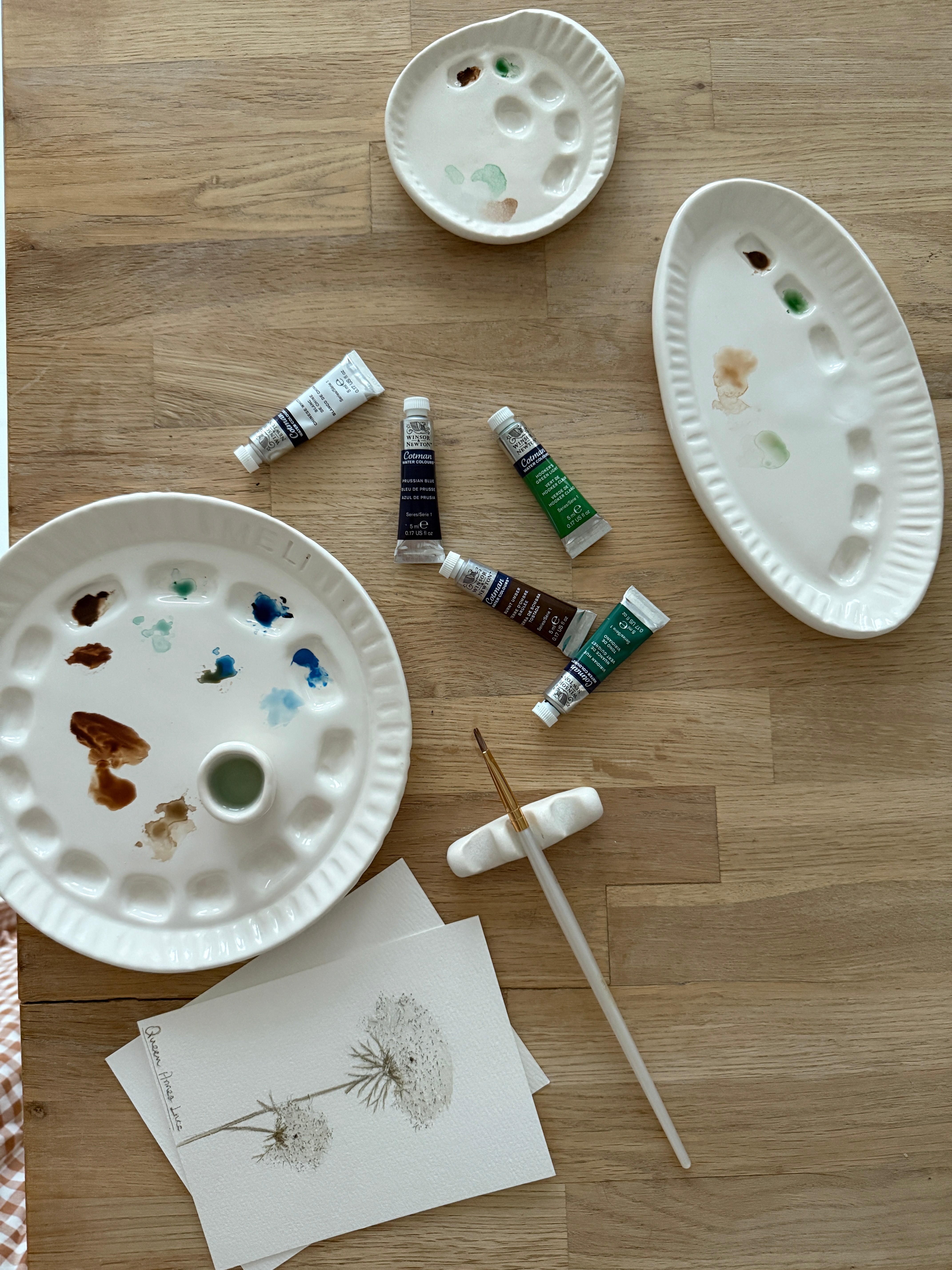 Handmade ceramic watercolor paint palette with mixing wells, a small water cup, and a brush holder.