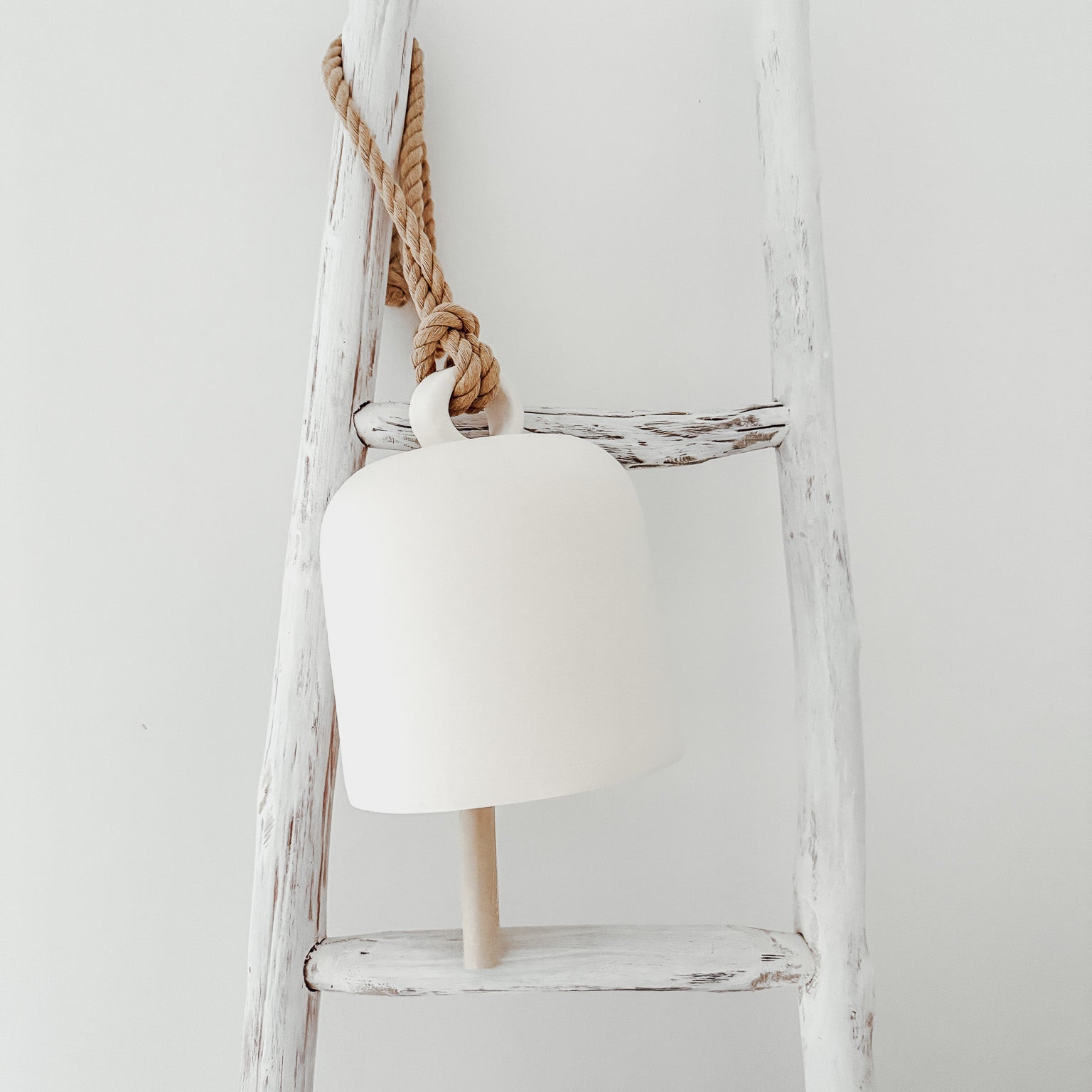 Handmade ceramic Loki bell in a neutral finish, hung for indoor or covered outdoor decor