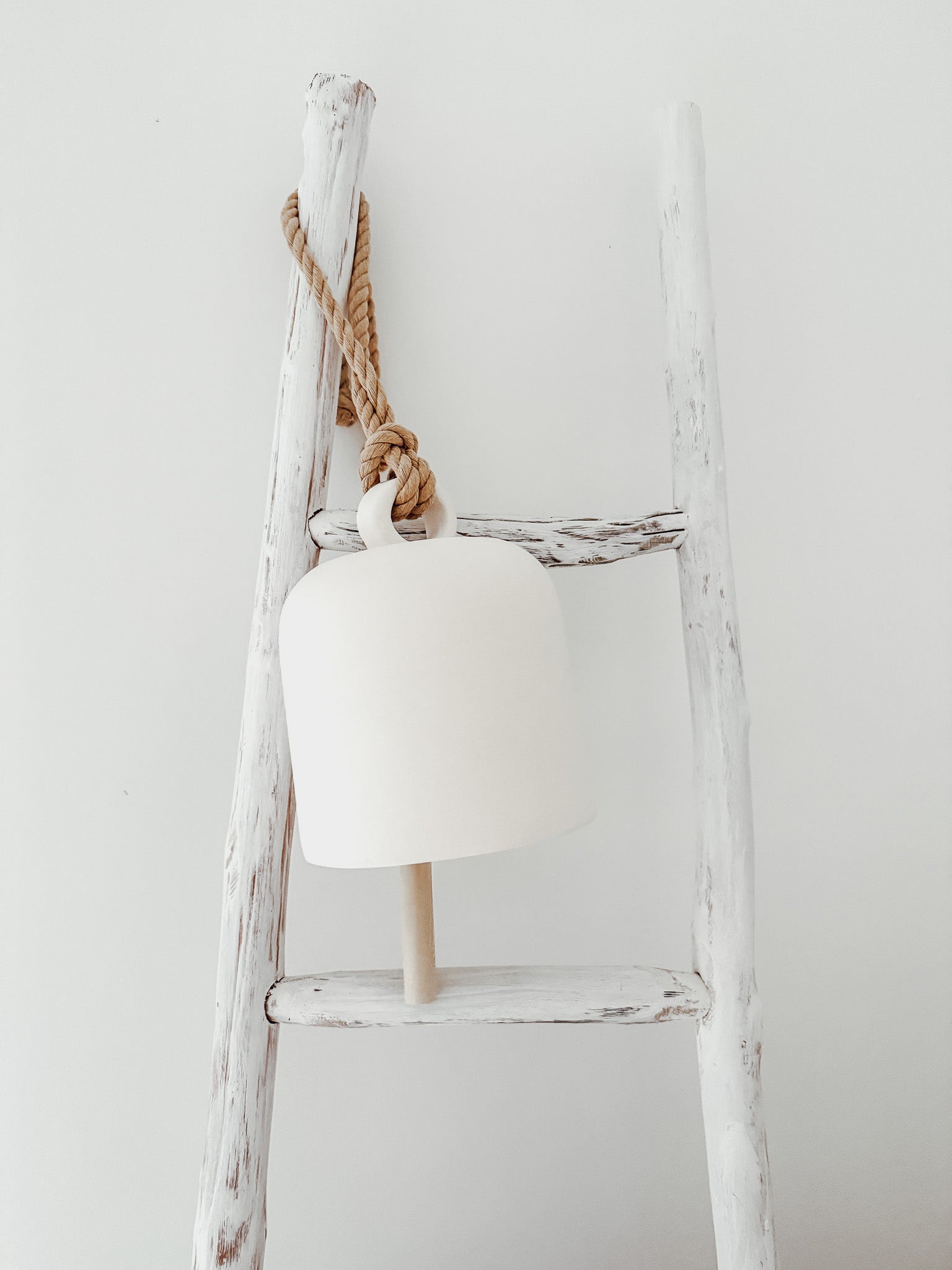 Handmade ceramic Loki bell in a neutral finish, hung for indoor or covered outdoor decor