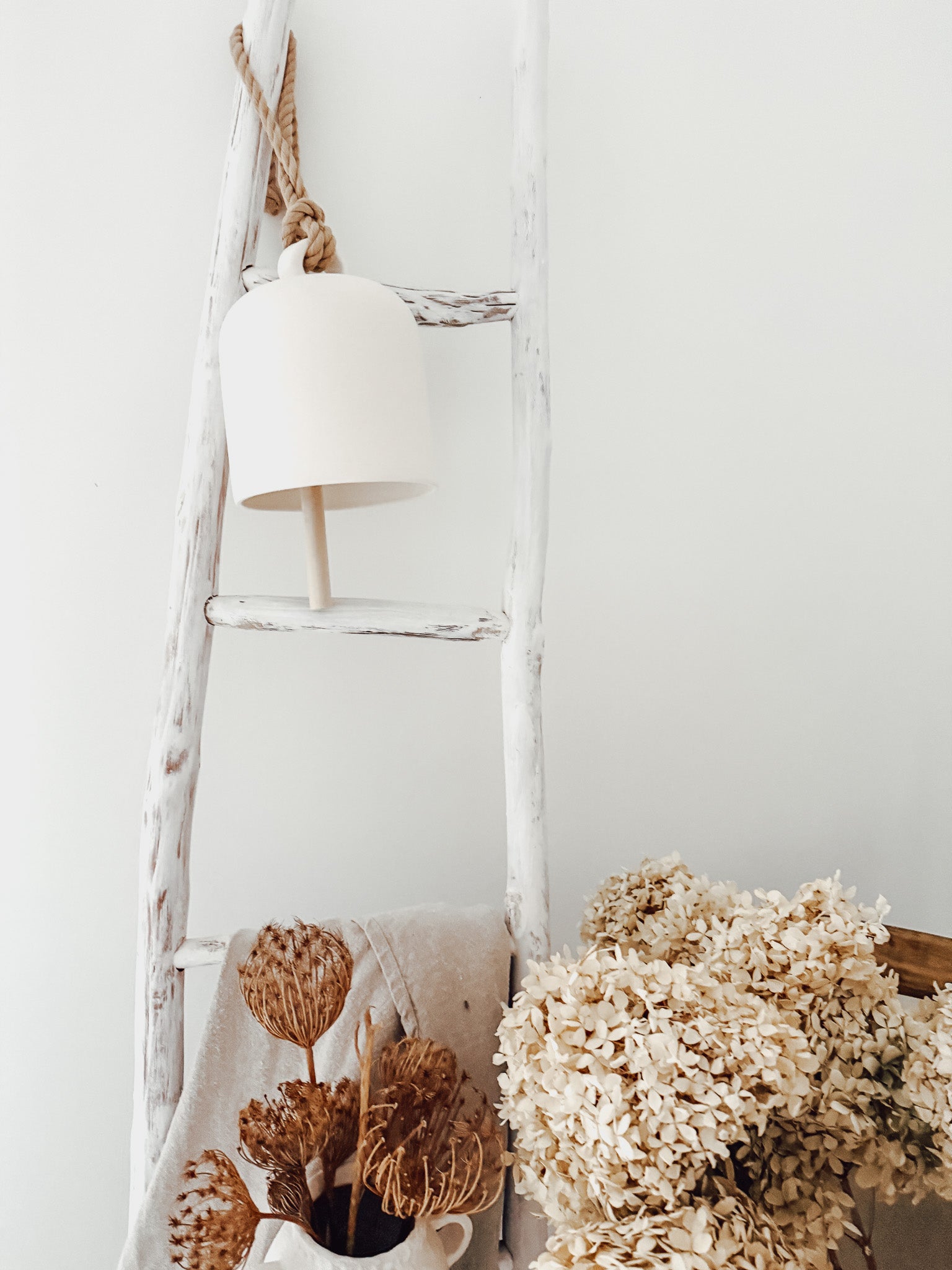 Handmade ceramic Loki bell in a neutral finish, hung for indoor or covered outdoor decor