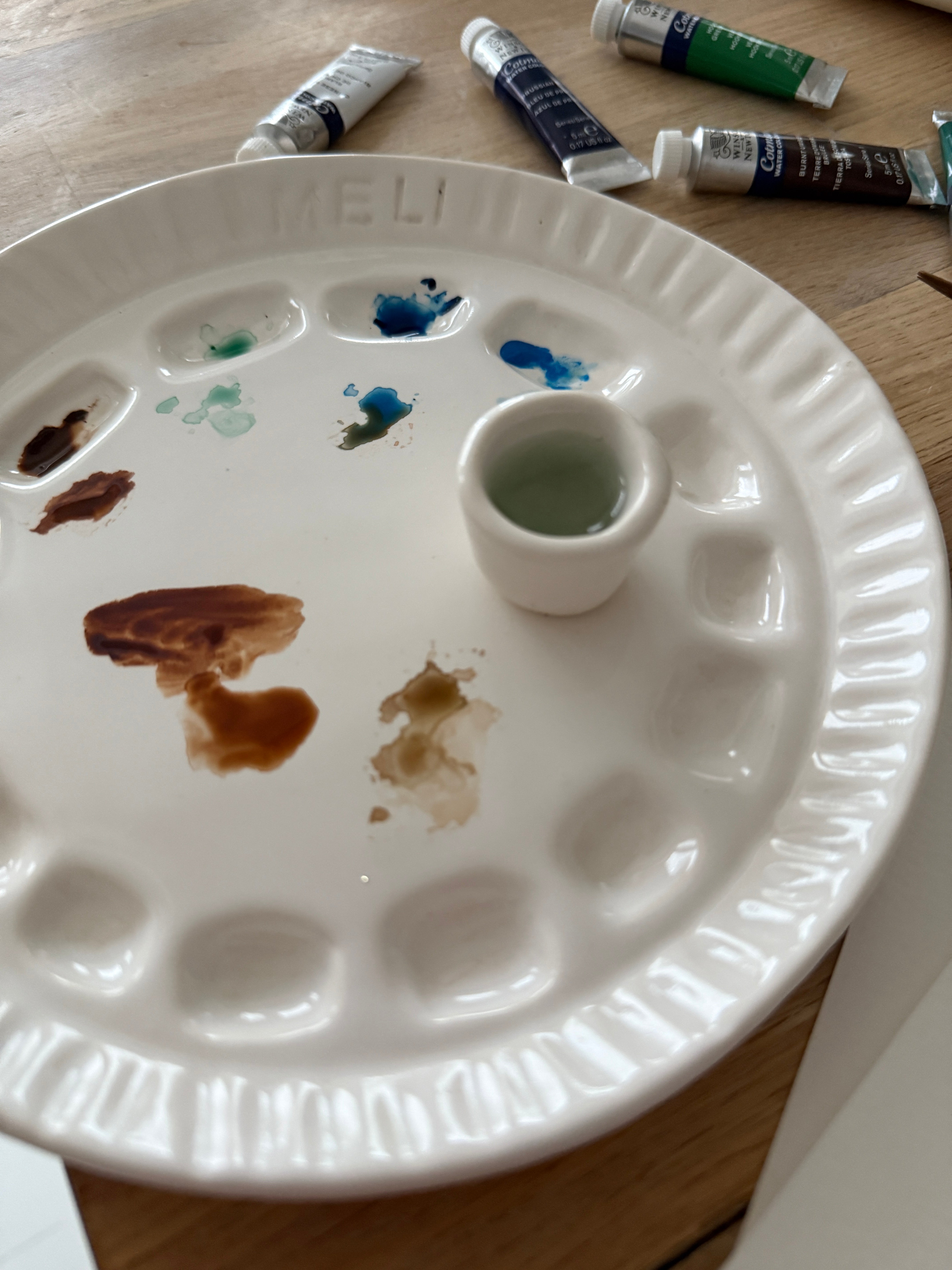 Handmade ceramic watercolor paint palette with mixing wells, a small water cup, and a brush holder.