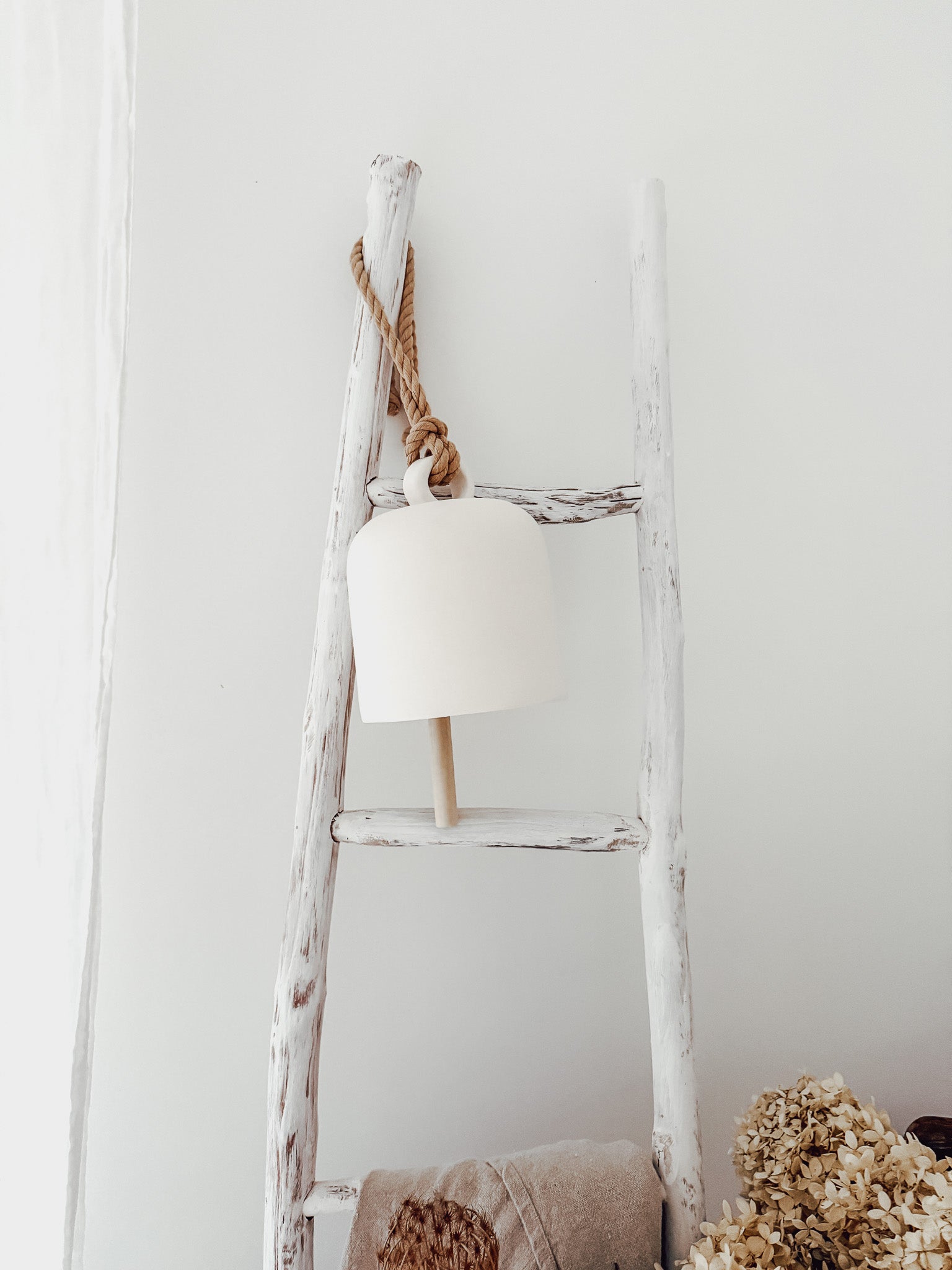 Handmade ceramic Loki bell in a neutral finish, hung for indoor or covered outdoor decor